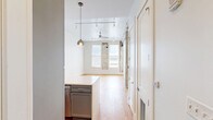 Located in the heart of New Orleans' historic French Quarter on Chartres Street, this one-bedroom, one-bathroom unit blends modern updates with charming historic character. The open-plan kitchen and living area serves as the centerpiece of the home, anchored by a sleek quartz waterfall island with an undermount sink and industrial-style faucet. The kitchen is outfitted with gray shaker cabinetry, stainless steel appliances including a gas range and refrigerator, herringbone tile backsplash, and stylish globe pendant lighting — creating a highly functional and visually polished space. Warm hardwood floors run throughout, complementing the crisp white walls and generous natural light admitted through large windows. Exposed original masonry columns in the living area and bedroom offer a distinctive nod to the building's historic roots, adding texture and character unique to New Orleans architecture. The bedroom is comfortably sized and features a double-door closet, track lighting, and a beadboard ceiling detail. The bathroom is finished with classic white subway tile surrounding the tub/shower combo, a wood-toned vanity with a white countertop, and tile flooring — clean, modern, and well-appointed throughout.