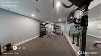 Located at 5341 Arrival Drive in Raleigh, NC, this dedicated exercise room is a fully outfitted private fitness space designed for a comprehensive workout experience. The room is finished with soft blue-gray walls and durable rubber-speckled flooring, providing both a clean aesthetic and a practical, impact-resistant surface ideal for high-intensity training.

The space is thoughtfully organized to maximize functionality. A multi-station cable machine anchors one side of the room, offering a wide range of strength training exercises. Opposite the machine, a full-length wall mirror expands the sense of space and allows for form monitoring during workouts. A wall-mounted flat-screen TV is positioned for convenient viewing during training sessions.

The free weight area features a tiered rack stocked with a complete set of dumbbells, kettlebells, and medicine balls, catering to varied training styles. An additional rack holds stability balls and resistance bands, rounding out the room's versatility. An adjustable workout bench sits centrally, ready for use with the surrounding equipment.

Recessed lighting illuminates the room evenly, while a window with blinds provides natural light and ventilation. The room is equipped with a wall-mounted sanitizing station and a stainless steel waste bin, maintaining a clean and professional environment. This exercise room delivers a well-rounded, private fitness facility suitable for strength, cardio, and functional training.