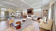 Located at 243 Steele Rd in West Hartford, CT, this sophisticated single-floor lounge space offers a refined and welcoming atmosphere defined by high-end architectural details and thoughtful design. The centerpiece of the room is a striking coffered ceiling with recessed lighting, which adds depth and a sense of grandeur to the open layout. Underfoot, richly patterned herringbone hardwood flooring anchors the space with warmth and texture.

A sleek, wall-mounted linear fireplace framed in warm wood paneling serves as a dramatic focal point, complemented by a wall-mounted flat-screen television above. Generous seating arrangements, including a large sectional sofa and accent chairs, are thoughtfully positioned to encourage conversation and relaxation.

Abundant natural light streams in through multiple sets of French doors and transom windows, connecting the interior to the outdoors and creating an airy, open ambiance. A built-in kitchenette area with warm wood cabinetry, a beverage refrigerator, and a Keurig station adds everyday convenience. Geometric-patterned hardwood flooring in the kitchenette nook further highlights the space's attention to detail. The overall aesthetic blends classic architectural elements with contemporary furnishings for a polished, community-centered environment.