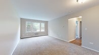 Located at 820 Ollie Ct in Carpentersville, Illinois, this single-floor home offers a clean, modern aesthetic with thoughtful updates throughout. The spacious living area is carpeted in neutral tones and features large windows that invite abundant natural light and views of the surrounding greenery, creating an open and airy feel. The updated kitchen is a standout, outfitted with gray shaker-style cabinetry, black hardware, marble-look countertops, and a full suite of black appliances including a gas range, dishwasher, and refrigerator. Light wood-look flooring grounds the kitchen and connects seamlessly to the hallway, which leads to the various rooms throughout the home. The bathroom features a gray vanity with marble-style countertops, a large mirror, and wood-look flooring, maintaining the home's cohesive modern palette. Bedrooms are carpeted and well-sized, with one room offering the convenience of dual sliding-door closets for generous storage. A connecting hallway with warm hardwood-style flooring ties the layout together efficiently. Neutral gray walls, white trim, and consistent finishes throughout give the home a polished, move-in-ready character suited for comfortable everyday living.