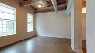 This 2-bedroom, 2-bathroom unit blends industrial character with modern finishes across a single floor. Exposed wooden beams and visible ductwork run across the ceilings, creating a loft-like aesthetic that adds warmth and architectural interest throughout the space. Polished concrete floors extend seamlessly from room to room, reflecting natural light and reinforcing the unit's contemporary industrial charm.

The open living area is generously proportioned, with neutral-toned walls and multiple windows that invite abundant natural light. The kitchen is well-appointed with white cabinetry, dark granite countertops, a stainless steel dishwasher, range, and microwave, complemented by a transom window above that connects visually to the beam-lined ceiling beyond.

Both bedrooms are spacious and bright, featuring the same polished concrete floors and exposed beam ceilings. Large windows in each room offer views to the outdoors, while one bedroom includes a structural column that adds to the loft character of the space.

The two bathrooms are clean and functional. One features a shower-tub combination with white cabinetry and concrete flooring, while the second offers a walk-in shower, a round mirror, and a white vanity with under-cabinet storage. Together, these elements create a cohesive, urban-inspired living environment.