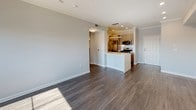 This well-designed single-floor residence offers a thoughtful layout that balances open communal spaces with comfortable private areas. The open-concept living and dining area is anchored by rich, dark hardwood-style flooring and crown molding, creating an elegant yet approachable ambiance. A sliding glass door floods the living room with natural light and opens to a private balcony overlooking city views. Built-in shelving adds a functional and decorative touch to the living space.

The kitchen is seamlessly integrated into the open floor plan and features stainless steel appliances, including a gas range, microwave, and French door refrigerator. Taupe cabinetry, a white tile backsplash, and a kitchen island with a clean white countertop complete the modern aesthetic.

The bedrooms are carpeted for comfort and benefit from large windows that invite natural light and exterior views. The primary suite includes a spacious walk-in closet with built-in shelving and hanging rods for ample storage.

Two well-appointed bathrooms serve the residence. One features a soaking tub/shower combination and a floating vanity with an integrated sink and backlit mirror. The second bathroom offers a corner glass-enclosed walk-in shower, a matching floating vanity, and a backlit mirror. Wood-look flooring runs throughout both bathrooms, tying the design together cohesively.