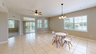 Located at 209 Cantabria Way in Saint Augustine, Florida, this well-appointed single-story home offers three bedrooms and three bathrooms across a generously sized floor plan. The living and dining areas are finished with large neutral-toned ceramic tiles, and an abundance of natural light pours in through multiple windows with blinds. The combined dining and living space features ceiling fans, a chandelier, and sliding glass doors that open to a screened balcony porch with lush tree views — ideal for outdoor relaxation.

The kitchen is equipped with rich warm-toned wood cabinetry, light countertops, recessed lighting, and stainless steel appliances including a range and built-in microwave. A curved peninsula adds functional counter space, and the kitchen connects directly to a dedicated laundry room housing a full-size washer and dryer with overhead wire shelving.

The bedrooms are carpeted and bright, each with ceiling fans and windows offering natural views. The spacious primary bedroom includes a large sliding-door closet and is complemented by an en-suite bathroom featuring a corner soaking tub, glass-enclosed shower, dual-sink vanity with wood cabinetry, and tile flooring. Secondary bathrooms include a tub-shower combo with tile surround. The home's neutral palette and practical layout make it a comfortable and functional residence.