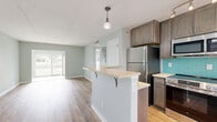 Located at 6742 Gulfport Blvd S in South Pasadena, FL, this thoughtfully updated single-story home offers four bedrooms and one bathroom across a compact, efficiently designed floor plan. The renovated kitchen is a standout feature, showcasing rich wood cabinetry, quartz countertops, stainless steel appliances including a range, microwave, and refrigerator, and a vibrant teal subway tile backsplash. A peninsula with a built-in wine cooler and bar seating adds both function and character, making the kitchen a central hub of the home. Light wood-tone luxury vinyl plank flooring runs throughout, lending warmth and continuity to every room. Each bedroom is finished in soft sage-green tones, with ceiling fans, ample natural light from slatted blinds, and closets with bifold doors for storage. The primary bedroom offers a generous footprint with outdoor views of lush greenery. The bathroom features a full soaking tub with bright white subway tile surround and a decorative mosaic accent border. A large window in the living area frames a tranquil waterfront view, filling the space with natural light and bringing the outdoors in. The exterior reveals a well-maintained green yard, completing this inviting Florida home.