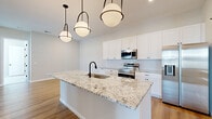 Located at 4985 Warner Rd. in Westerville, Ohio, this well-appointed single-story home offers three bedrooms, two bathrooms, and a thoughtfully designed layout across a comfortable footprint. The interior showcases a clean, contemporary aesthetic with light-toned walls, luxury vinyl plank flooring throughout the main living areas, and plush carpet in the bedrooms.

The kitchen is a standout feature, boasting an oversized granite island with an undermount sink and matte black faucet, crisp white shaker cabinetry, a subway tile backsplash, and a full suite of stainless steel appliances. Statement globe pendant lights add a modern touch overhead. The kitchen flows seamlessly into the dining area, making it ideal for entertaining.

The primary bedroom is generously sized, with direct access to a dedicated bathroom featuring a walk-in glass-enclosed shower with tile surround, a dark-toned vanity with granite countertop, and warm wood-look flooring. The secondary bathroom includes a full tub-shower combo with oil-rubbed bronze fixtures.

Secondary bedrooms are bright and inviting, each featuring large windows with blinds and closet access. The home also includes five closets in total—including spacious walk-in closets with wire shelving—as well as a dedicated laundry room and a central hallway connecting all areas of the home.