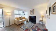 This single-floor, 1-bedroom, 1-bathroom unit offers a practical and comfortable layout designed to maximize every square foot. The living room serves as the heart of the home, featuring plush wall-to-wall carpeting, a striking black-surround fireplace, and large windows with vertical blinds that invite natural light and offer outdoor views. The space flows seamlessly into a dedicated dining area, which provides ample room for a full dining table and chairs, making it ideal for everyday meals or entertaining. The kitchen is efficiently designed with dark cabinetry contrasted by light countertops, wood-style flooring, a dishwasher, and a full-size refrigerator. A tall window above the counter brings in additional natural light and a view of the surrounding greenery. The bedroom is generously sized, accommodating a full bed with room to spare, and features large windows, soft carpeting, and a sliding-door closet offering convenient built-in storage. The full bathroom includes a combined tub and shower, a dark-vanity sink, and wood-style flooring, completing the unit with a clean, functional finish throughout.