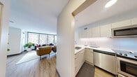 Located at 420 East Ohio Street in Chicago's vibrant Streeterville neighborhood, this efficiently designed single-floor unit offers a smart, modern layout that maximizes every square foot. The open-concept kitchen and living area form the heart of the space, bathed in natural light streaming through large floor-to-ceiling windows that frame impressive urban skyline views. The kitchen is outfitted with sleek, flat-front cabinetry in a light wood finish, crisp white quartz countertops, stainless steel appliances including a range, dishwasher, microwave, and refrigerator, and a peninsula with bar seating that doubles as a casual dining area. Light wood-tone flooring flows seamlessly throughout, lending warmth to the contemporary design. The living area is generously proportioned for its footprint, with bright white walls and wide windows continuing the airy, open feel. The full bathroom features a tiled tub-shower combination with clean, neutral finishes. Throughout the unit, the design aesthetic is modern and cohesive, with a neutral palette and quality finishes that create a polished, functional living environment well-suited to urban life in the heart of Chicago.