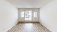 Located in the Ellerslie neighbourhood of southwest Edmonton, this 2-bedroom, 2-bathroom unit offers a practical and well-finished single-floor layout. Light wood laminate flooring runs throughout the main living areas, complemented by textured ceilings and crisp white walls that create a clean, bright atmosphere.

The open-concept living and dining area is generously sized, anchored by a pendant light fixture and vertical blinds that filter natural light. A sliding glass door leads to a private balcony, extending the living space outdoors. The kitchen features warm wood cabinetry, granite-style countertops, a mosaic tile backsplash, and black appliances including a full-size refrigerator, stove, and dishwasher — with frosted glass doors adding a refined touch nearby.

The primary bedroom is a comfortable size with a window overlooking the exterior, while the second bedroom offers similar light and laminate flooring. Both bathrooms are well-appointed with granite-topped vanities and warm wood cabinetry; one includes a walk-in shower with sliding glass doors, and the other a full soaker tub. A dedicated laundry area houses a stacked washer and dryer unit with built-in shelving. Four closets throughout provide excellent storage.