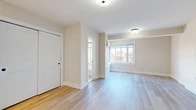This well-appointed single-floor space has been thoughtfully updated with a clean, modern aesthetic that is evident throughout. Light-toned hardwood flooring flows seamlessly across the main living areas, complementing the warm neutral wall tones and white trim that give the space an open, airy feel. The main living area is generously proportioned, featuring a large multi-pane window that frames views of the surrounding neighborhood and draws in abundant natural light. A built-in closet with a classic panel door provides convenient storage.

The kitchen is efficiently designed and well-equipped, featuring crisp white shaker-style cabinetry extending to the ceiling for maximum storage, a white subway tile backsplash, and stainless steel appliances including a refrigerator, gas range, and range hood. Light hardwood flooring continues into this space, maintaining visual continuity.

The bathroom is finished in a clean, timeless style with white subway tile wainscoting, a soaking tub, and a sleek vanity with white stone countertop and matte black fixtures. A frosted glass window provides privacy while allowing natural light to filter in. Overall, the space presents a fresh, move-in-ready environment with a cohesive design language and quality finishes throughout.