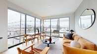 Located at 49 Fisk St in Jersey City, NJ, this modern two-bedroom, two-bathroom residence offers a thoughtfully designed single-floor layout with contemporary finishes throughout. The open-concept living, dining, and kitchen area is the heart of the home, anchored by expansive floor-to-ceiling windows that flood the space with natural light and frame sweeping urban views of the surrounding cityscape. Light hardwood flooring runs throughout, lending warmth to the clean, modern aesthetic.

The kitchen features sleek light wood cabinetry, a blue-gray tile backsplash, stainless steel appliances, and a freestanding island with bar seating — ideal for both casual dining and entertaining. The combined dining and living area benefits from the dramatic window wall, creating an airy, connected atmosphere.

The primary bedroom is generously proportioned, offering a tranquil retreat with a large window and views of the city. The second bedroom is versatile, also featuring a window with city views. Both bathrooms are finished in a contemporary style with large-format gray tile, light wood vanities with black hardware, framed mirrors, and overhead cabinetry. One bathroom includes a glass-enclosed walk-in shower, while the other features a soaking tub. This residence delivers modern urban living in a bright, well-appointed package.