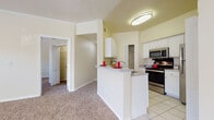 Located at 1210 Westbury Pointe Dr in Brandon, Florida, this single-story home offers a well-designed layout with a warm, neutral color palette throughout. The open-concept kitchen is a functional centerpiece, featuring white cabinetry with ample storage, granite-style countertops, a breakfast bar peninsula, and stainless steel appliances including an electric range, over-the-range microwave, and dishwasher. Light tile flooring runs through the kitchen, while plush wall-to-wall carpeting extends across the living areas and bedrooms, adding comfort underfoot. The spacious living area is bathed in natural light from multiple windows and is accented by a ceiling fan overhead. The bedrooms are generously sized, each with carpeted floors, neutral walls, and ceiling fans, creating comfortable and functional retreats. Closet space is provided via louvered bi-fold doors. The home includes two bathrooms: one featuring a walk-in glass-enclosed shower, white vanity cabinetry, and tile flooring, and a second full bathroom with a tub-shower combination. Vaulted ceilings in the kitchen and adjoining areas lend an airy, open feel to the interior. Clean white trim and soft beige tones throughout create a cohesive and inviting atmosphere.