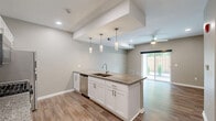 Located at 2400 N Forest Rd in Getzville, NY, this well-appointed 2-bedroom, 2-bathroom single-floor residence offers a thoughtfully designed layout with modern finishes throughout. The open-concept kitchen and living area serves as the heart of the home, featuring a peninsula with granite countertops, a double sink, and pendant lighting above. White shaker-style cabinetry, stainless steel appliances—including a gas range, microwave, and refrigerator—and light wood-look flooring complete the kitchen's clean, contemporary aesthetic. A sliding glass door in the living area fills the space with natural light and provides views of the outdoor surroundings. The two bedrooms are carpeted for comfort, with neutral wall tones and ample natural light. The generously sized primary bedroom includes a walk-in closet outfitted with wire shelving for organized storage. Both bathrooms are finished in a clean, neutral palette, with one featuring a full tub-shower combination. A dedicated laundry room and an additional closet add practical convenience. The space also includes a separate room with hard flooring, suitable for a home office or flex space. Ceiling fans, recessed lighting, and consistent neutral tones create a cohesive and comfortable living environment throughout.