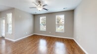 Located at 355 Amistead Ave in Fort Mill, South Carolina, this single-floor residence offers a well-designed layout with contemporary finishes throughout. The kitchen is a standout feature, showcasing light wood cabinetry, granite countertops, a classic white subway tile backsplash, and a full suite of stainless steel appliances including a range, over-the-range microwave, dishwasher, and refrigerator. Warm hardwood-style flooring flows through the main living and kitchen areas, creating a cohesive and inviting atmosphere. The entry area provides a welcoming transition into the open living space, with multiple doors offering convenient access to storage and additional rooms. Living and dining areas benefit from ceiling fans and large windows fitted with blinds, allowing natural light to fill the space while providing outdoor views of the surrounding community. Bedrooms are finished with plush carpeting and neutral-toned walls, each featuring ceiling fans and dual windows that enhance airflow and brightness. The bathroom is appointed with a granite-topped vanity, wood-toned cabinetry, hardwood-style flooring, and a full tub-shower combination. Neutral gray walls and clean white trim are consistent throughout, contributing to a modern, move-in-ready aesthetic.