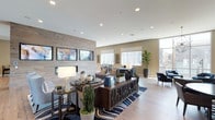 The 1660 Metro Clubhouse in Chula Vista is a thoughtfully designed single-floor community amenity space that blends modern aesthetics with functional comfort. The welcoming entry features light hardwood flooring, bold blue accent chairs, curated wall art, and tall indoor plants that set an inviting tone throughout.

The main lounge area is anchored by a textured wood-panel feature wall with mounted flat-screen displays, a linear fireplace, and stylish furniture arrangements centered on a bold striped area rug. Floor-to-ceiling windows in the seating nook flood the space with natural light and offer views of the surrounding neighborhood, complemented by a striking geometric chandelier overhead.

The fully equipped kitchen is a standout feature, boasting dark cabinetry with a professional-grade gas range, stainless steel appliances including a full-size refrigerator, a large quartz island with an undermount sink, marble-style backsplash, and warm brass pendant lighting — ideal for community gatherings and events.

The game room offers a billiards table with a wall-mounted cue rack, decorative billiard ball artwork, and a high-top table for casual socializing. A dedicated card and game table area features a round poker-style table with built-in seating, bathed in natural light from nearby windows. Throughout the space, curated artwork and lush greenery add warmth and personality.