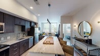 This single-floor residence is designed with a contemporary aesthetic, combining functional layouts with modern finishes throughout. The open-concept kitchen flows seamlessly into the living and dining areas, creating a cohesive and sociable space. The kitchen is appointed with rich dark-espresso cabinetry, granite countertops, a tiled backsplash, and a full suite of stainless steel appliances, including a range, microwave, dishwasher, and refrigerator. A spacious granite-topped island with seating anchors the kitchen, offering additional prep space and casual dining options. Pendant lighting above the island adds a stylish focal point. Light wood-style flooring runs throughout the main living areas, complementing the neutral color palette.

The living room is generously proportioned, featuring a ceiling fan, large windows that invite abundant natural light, and views of the surrounding exterior. The two bedrooms are well-sized, each with large windows offering outdoor views and ample room for furnishings. In-unit laundry is conveniently tucked within the floorplan. The bathroom features a granite-topped dark wood vanity with an undermount sink, a large mirror, and a walk-in shower. Recessed lighting throughout ensures a bright, polished atmosphere.