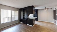 Located at 1707 Essex in San Diego, Unit #41 at The Ambassador is a single-floor residence designed with a practical and cohesive aesthetic throughout. The open-concept living and dining area is finished with warm wood-look flooring, neutral wall tones, and a textured ceiling. A ceiling fan overhead and a large window fitted with vertical blinds allow for natural light and air circulation, creating a comfortable and functional living space.

The kitchen is a standout feature, showcasing bold dark cabinetry that extends floor to ceiling, offering generous storage alongside a built-in open shelving unit. A peninsula with a granite-style countertop provides both additional prep space and a casual bar-style seating area. Stainless steel appliances, including a dishwasher, range, and refrigerator, complete the well-equipped kitchen, which also benefits from its own window for natural light.

The bedroom is a well-proportioned retreat with the same wood-look flooring, a wide window for natural light, and a dedicated closet for storage. The bathroom features a dark-cabinet vanity with a stone-look countertop, a large mirror, and a combined tub and shower enclosure, delivering a clean and functional design. Throughout the unit, consistent finishes and a neutral palette create a unified and move-in-ready environment.