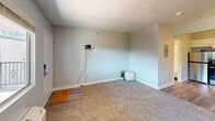 This 300 square foot studio apartment in Las Vegas offers a thoughtful layout that maximizes efficiency in a compact space. The modern kitchen is a standout feature, boasting white cabinetry, stainless steel appliances including a refrigerator and range, and a sleek backsplash. The living area is carpeted and features a large window, providing natural light and a view of the surrounding area. A wall-mounted air conditioning unit ensures comfort year-round.

The bathroom, while compact, includes a full-sized tub with a shower, a modern vanity, and is finished with light-colored walls and flooring. A closet provides essential storage space. The apartment's flooring transitions from carpet in the living area to what appears to be vinyl or laminate in the kitchen and bathroom, adding visual interest and practicality.

The unit's single-floor design and open concept maximize the use of space, making it feel larger than its 300 square feet. The neutral color palette throughout creates a bright, airy atmosphere. This apartment would be ideal for a single occupant or couple looking for a modern, low-maintenance living space in a convenient Las Vegas location.