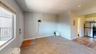 This 300 square foot studio apartment in Las Vegas offers a thoughtful layout that maximizes efficiency in a compact space. The modern kitchen is a standout feature, boasting white cabinetry, stainless steel appliances including a refrigerator and range, and a sleek backsplash. The living area is carpeted and features a large window, providing natural light and a view of the surrounding area. A wall-mounted air conditioning unit ensures comfort year-round.

The bathroom, while compact, includes a full-sized tub with a shower, a modern vanity, and is finished with light-colored walls and flooring. A closet provides essential storage space. The apartment's flooring transitions from carpet in the living area to what appears to be vinyl or laminate in the kitchen and bathroom, adding visual interest and practicality.

The unit's single-floor design and open concept maximize the use of space, making it feel larger than its 300 square feet. The neutral color palette throughout creates a bright, airy atmosphere. This apartment would be ideal for a single occupant or couple looking for a modern, low-maintenance living space in a convenient Las Vegas location.