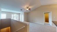This single-floor home offers a thoughtfully designed layout with a range of practical and comfortable features throughout. The main living area is a standout, boasting vaulted ceilings and a ceiling fan that contribute to an open, airy atmosphere. Plush wall-to-wall carpeting runs throughout the living and bedroom spaces, and large arched windows and glass doors allow natural light to fill the room while providing views of the outdoors. A low half-wall divides the living space, adding architectural interest while maintaining an open feel.

The galley-style kitchen is efficiently designed, featuring white cabinetry, dark granite-style countertops, tile flooring, and black appliances including a refrigerator, electric range with overhead microwave, and dishwasher. A double stainless steel sink and ample cabinet storage complete the functional space.

The bedrooms are carpeted and well-lit, each with vaulted or angled ceilings and ceiling fans. Windows with blinds provide natural light and privacy. The bathroom includes tile flooring, a granite-topped vanity with white cabinetry, a tiled tub/shower combination, and a lighted vanity mirror. A dedicated in-unit laundry area with a washer and overhead shelving adds everyday convenience to this well-rounded home.