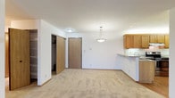 This single-floor residence offers a thoughtfully designed layout that balances comfort and functionality throughout. The open living area is generously sized, finished with neutral-toned wall-to-wall carpeting and crisp white walls that create a bright, welcoming atmosphere. A pendant light fixture serves as a focal point, while a convenient closet with built-in shelving adds practical storage near the entryway.

The kitchen is a standout feature, showcasing warm honey-toned cabinetry, granite-style countertops, and stainless steel appliances including a range and refrigerator. A breakfast bar peninsula seamlessly connects the kitchen to the living space, making it ideal for both everyday meals and entertaining. The kitchen is finished with easy-care hardwood-style flooring.

The bedrooms are carpeted and well-lit, with one room featuring a ceiling fan and a window overlooking outdoor greenery, while another offers a sliding window with views to the exterior. Each room includes a closet and ample wall space.

Two full bathrooms serve the residence, each featuring a wide vanity with a single sink, large mirrors with overhead lighting, tile flooring, and chrome hardware accents. The overall design is clean, neutral, and move-in ready.