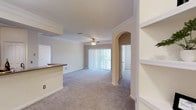 This single-floor residence offers a thoughtfully designed open-concept layout that seamlessly connects the living, dining, and kitchen areas. The living room is finished with plush wall-to-wall carpeting, crown molding, a ceiling fan with light fixture, and a large sliding glass door fitted with vertical blinds that allows abundant natural light and outdoor views. Built-in shelving and an elegant arched passageway add architectural character to the space.

The kitchen is well-equipped with light wood cabinetry, stainless steel appliances including a refrigerator, electric range, over-the-range microwave, and dishwasher, complemented by tile flooring, a tiled backsplash, and a peninsula with countertop seating that opens to the living area.

The bedrooms are carpeted and generously sized, each featuring a ceiling fan and ample natural light. Both bedrooms include walk-in closets, and one bedroom offers direct access to a private en-suite bathroom. The two full bathrooms are similarly appointed with tiled tub-shower combinations accented by decorative diamond-pattern tiles, large vanity mirrors, and neutral cabinetry.

A dedicated laundry area houses a full-size washer and dryer with overhead shelving, adding everyday convenience. Throughout the residence, a consistent neutral color palette and clean finishes create a cohesive and inviting atmosphere.