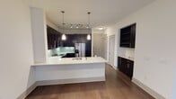 Located at 3509 N Grapevine Mills Blvd in Grapevine, TX, this single-floor unit showcases a contemporary design with a cohesive, open layout. Rich dark hardwood flooring flows throughout the main living areas, lending warmth and contrast against the crisp white walls and ceilings.

The kitchen is a standout feature, equipped with dark espresso cabinetry that extends to the ceiling, sleek white countertops, a subway tile backsplash, and a full suite of stainless steel appliances including a refrigerator with ice maker, range, microwave, and dishwasher. A large center island with pendant lighting provides additional prep space and casual seating. A built-in shelving unit and a dedicated wet bar area with additional cabinetry add both function and character nearby.

The open living area is bright and generously proportioned, benefiting from natural light through French doors that lead to an exterior access point. Track lighting and a ceiling fan complement the space.

The bathroom features a dual-sink vanity with dark cabinetry and a wide mirror, tile flooring, and a combination tub and shower with tile surround. A carpeted bedroom with a ceiling fan and a window with natural light completes the layout, offering a comfortable and quiet retreat.