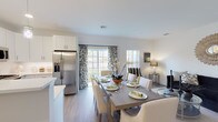Located at Cornerstone at Hauppauge in Hauppauge, NY, this single-floor residence combines modern design with functional living. A welcoming entryway greets you with light wood-tone flooring that carries throughout the main living areas, setting a clean and cohesive tone from the start. The entry features a stylish console and a large decorative mirror, offering an elegant first impression before opening into the heart of the home. The living room is a comfortable, well-proportioned space highlighted by neutral walls, a sunburst wall accent, and generous natural light. Adjacent to it, a dedicated sitting or flex area provides additional versatility. The open-concept kitchen is a standout feature, outfitted with crisp white shaker cabinetry, quartz countertops, a subway tile backsplash, stainless steel appliances including a gas range and built-in microwave, and pendant lighting above the peninsula with bar seating. The dining area flows seamlessly from the kitchen and is bathed in natural light from large windows dressed with decorative curtains. The bedroom is generously sized with plush carpeting, ample natural light, and a calm, neutral palette. The bathroom is finished with large-format tile flooring, a dark vanity with white countertop, and a clean, bright design. Every detail of this residence reflects a modern, refined sensibility.