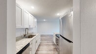 Located at 1603 W Viking Ct in Peoria, IL, this single-floor, one-bedroom, one-bathroom unit offers a thoughtfully designed layout with modern finishes throughout. Light-toned luxury vinyl plank flooring runs continuously through every room, lending a clean, cohesive aesthetic to the entire space.

The galley-style kitchen is a standout feature, showcasing white shaker cabinetry, granite-look countertops, a stainless steel undermount sink with a modern pull-down faucet, and a full suite of stainless steel appliances including a refrigerator, electric range, microwave, and dishwasher. Recessed lighting and a textured ceiling complete the kitchen's polished look.

The living area is bright and open, with a sliding glass door leading to a private balcony with metal railing, allowing natural light to fill the space. The bedroom is generously sized, offering a comfortable layout with direct access to the bathroom and ample closet space, including a walk-in closet with built-in shelving. Neutral wall tones throughout the unit create a versatile backdrop. The textured ceilings are consistent across all rooms, adding a classic residential character to this move-in ready home.