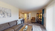 Located at 3401-A Queensway Dr in Erlanger, Kentucky, this well-appointed single-floor residence offers a thoughtfully designed layout with a warm, neutral color palette throughout. The living room serves as the heart of the home, featuring durable wood-look flooring, a large sliding glass door with vertical blinds that invites abundant natural light, and comfortable space for both relaxing and entertaining. An open-concept connection leads to the dining area, which accommodates a round table and chairs, seamlessly adjoining the kitchen. The galley-style kitchen is well-equipped with white cabinetry, granite-look countertops, stainless steel appliances including a refrigerator, range, and dishwasher, and a deep undermount sink. The bedroom is carpeted for comfort and features windows with natural light, ample wall space, and access to a full bathroom with a shower-tub combination, white vanity, and wood-look flooring. A second bathroom with a white vanity and toilet provides added convenience for guests. Flanking the primary bathroom entrance are two open closets offering generous storage. Throughout the residence, consistent neutral tones, clean finishes, and functional design elements contribute to a cohesive and inviting living environment.