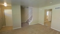 This multi-story residence spans three floors, offering a versatile layout designed to accommodate a variety of living arrangements. The main living area is finished with wall-to-wall carpeting in a warm, neutral tone that adds a sense of comfort underfoot. Smooth, light beige walls run throughout the space, creating a clean and cohesive aesthetic that allows for easy personalization with furnishings and décor.

A classic white-painted staircase with a traditional baluster railing serves as a central architectural feature, connecting the floors with a timeless, clean-lined design. The staircase is positioned to allow for an open feel in the main living space, with sight lines extending across the room.

Doorways and open passages lead to adjoining rooms, hinting at a functional and well-connected floor plan across all three levels. White baseboards provide a crisp contrast against the neutral walls and carpet, adding a finished, polished look throughout. The overall ambiance is understated and move-in ready, presenting a blank canvas well-suited for customization. The multi-floor layout provides natural separation between living, sleeping, and utility spaces, making this a practical and spacious property.