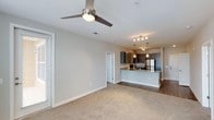 Located at 4001 Reedybrook Crossing in Apex, NC, this single-floor residence offers a clean, modern aesthetic with an open-concept design that seamlessly connects the living and kitchen areas. The living space features plush carpeting and a sleek ceiling fan with integrated lighting, creating a comfortable and well-ventilated environment. Neutral-toned walls throughout lend a bright, airy feel to the interior.

The kitchen is a standout feature, showcasing warm-toned cabinetry paired with light granite countertops and a kitchen island with a built-in sink that doubles as a breakfast bar. Stainless steel appliances add a contemporary touch, while pendant lighting and adjustable track lighting illuminate the space with both function and style. The transition from carpeted living areas to hardwood-style flooring in the kitchen creates a natural visual separation between the two spaces.

The layout is thoughtfully designed to maximize flow and accessibility, with interior doors providing access to additional rooms or storage. The overall ambiance is fresh and move-in ready, combining modern finishes with practical design elements that cater to everyday living. This residence offers a well-appointed, contemporary living experience in the heart of Apex, NC.