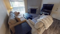 Located at 14901 SE 272nd St, Unit E202 in Kent, Washington, this single-floor residence offers a well-organized layout with comfortable living spaces throughout. The living room serves as the heart of the home, featuring a tiled fireplace with a classic white mantel that anchors the room. A sliding glass door with vertical blinds opens to a private balcony, allowing natural light to fill the carpeted space. The kitchen is efficiently designed with warm oak cabinetry, light countertops, and wood-look vinyl flooring. White appliances, including a range and refrigerator, are neatly arranged alongside ample upper cabinet storage and a built-in range hood. The two bedrooms are carpeted and offer a calm, neutral atmosphere. One bedroom includes a walk-in closet with built-in shelving, while the other features a window with vertical blinds that brings in natural light. Both rooms are well-proportioned and provide comfortable accommodations. The bathroom is finished with wood-toned cabinetry, a single vanity with a light countertop, vinyl plank flooring, and a shower-tub combination. Overall, the unit presents a functional and welcoming living environment in a residential setting in Kent, WA.