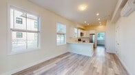 Located at 40 Pleasant St in Barnstable, Massachusetts, this single-floor unit offers a clean, contemporary design with a bright and airy atmosphere throughout. Light-toned hardwood-style flooring runs seamlessly across every room, contributing to a cohesive and modern aesthetic.

The open-concept living and kitchen area serves as the heart of the unit. Multiple large windows flood the space with abundant natural light, enhancing the warm, neutral palette of the walls and creating an inviting, spacious feel. The kitchen is well-appointed with crisp white Shaker-style cabinetry, light countertops, and a full suite of stainless steel appliances including a refrigerator, electric range, over-the-range microwave, and a sink. A peninsula counter extends into the living area, providing additional workspace and a natural division between the kitchen and living space.

The entryway features a secure front door alongside a large window that frames views of the surrounding greenery, welcoming natural light from the moment you step inside. A dedicated bedroom offers a quiet retreat with its own window overlooking the exterior, fitted with blinds for privacy. The bathroom is finished with clean, simple fixtures including hardwood-style flooring and grab bar hardware, reflecting a practical and accessible design sensibility. The overall layout is thoughtfully organized, maximizing functionality and comfort within a compact, single-level footprint.