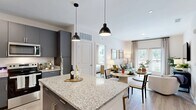 Located at 12801 Lucks Lane in Midlothian, VA, this single-floor, 2-bedroom, 2-bathroom residence offers a thoughtfully designed open-concept layout. The kitchen is a standout feature, showcasing sleek charcoal-gray cabinetry, granite countertops, a subway tile backsplash, stainless steel appliances, and a central island with pendant lighting and bar seating — ideal for both cooking and casual dining. The kitchen flows seamlessly into the living and dining areas, where light wood-style flooring, large windows, and natural light create a bright, welcoming ambiance. The primary bedroom is a comfortable retreat with plush carpeting, a ceiling fan, and a generously sized window offering outdoor views. The second bedroom features a distinctive sage-green accent wall with board-and-batten detailing, adding a touch of character. Both bathrooms are finished with granite-topped vanities, gray cabinetry, and clean white tile work; one features a glass-enclosed walk-in shower with subway tile surround and patterned floor tile. Additional spaces include two hallways and two closets, providing practical storage throughout. The overall aesthetic is modern and cohesive, blending contemporary finishes with a warm, livable feel.