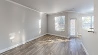 This single-floor residence offers a thoughtfully designed layout with modern finishes throughout. The open-concept living area features wood-look flooring and crown molding, with natural light streaming in through large windows. The kitchen is well-equipped with white shaker-style cabinetry, granite-look countertops, stainless steel appliances, a double-basin sink, and a textured tile backsplash — all flowing seamlessly into the living space via a breakfast bar pass-through. The bedrooms are carpeted for comfort, each with a ceiling fan and natural light from exterior-facing windows. The primary bedroom stands out with direct access to both a spacious walk-in closet fitted with wire shelving systems and a full en-suite bathroom. The bathroom features a dual-sink vanity with granite-look countertops, white cabinetry, a large mirror with vanity lighting, wood-look flooring, and a soaking tub with a shower combination. A generous walk-in closet with wrap-around wire shelving provides ample storage. The overall palette is neutral and contemporary, with soft gray walls, white trim, and consistent flooring choices that create a cohesive and clean aesthetic throughout the home.