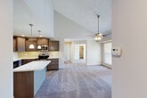 Located on Lake Lansing Road in Lansing, Michigan, this well-appointed 2-bedroom, 2-bathroom single-floor residence offers a thoughtfully designed layout with a range of quality finishes throughout. The open-concept kitchen and living area is an immediate highlight, featuring soaring vaulted ceilings and a ceiling fan that enhance the sense of spaciousness. The kitchen is equipped with rich dark-stained cabinetry, light granite countertops, a subway tile backsplash, stainless steel appliances including a refrigerator, range, microwave, and dishwasher, and a central island providing additional prep and seating space. Pendant lighting and recessed fixtures complete the kitchen's polished look. The living area flows naturally from the kitchen, showcasing a fireplace feature wall and large windows that invite natural light. A private balcony extends the living space outdoors. Both bedrooms are carpeted and generously sized, with the primary bedroom offering access to a closet. The second bedroom benefits from a charming bay window with outdoor views. The bathrooms feature granite vanity countertops, dark cabinetry, and a glass-door shower enclosure. A dedicated in-unit laundry room with shelving, four closets, and a welcoming entrance complete this functional and comfortable residence.