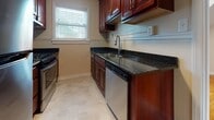 This thoughtfully designed single-floor space showcases a blend of classic character and functional updates throughout. The living areas are anchored by gleaming hardwood floors that run throughout, reflecting warm light and adding a sense of timeless appeal. Distinctive angled, sloped ceilings follow the roofline, giving the rooms a cozy, architectural charm while adding visual interest and a sense of depth.

The kitchen is well-equipped, featuring rich cherry wood cabinetry, dark granite countertops, stainless steel appliances including a gas range and dishwasher, and a deep undermount sink. A window above the counter fills the space with natural light. Light-toned tile flooring completes the kitchen's clean, polished look.

The bathroom retains a classic aesthetic with white subway tile walls accented by bold black border trim, a striking terracotta and white patterned tile floor, a white vanity with under-cabinet storage, and a soaking tub. A framed mirror and overhead lighting complete the functional yet stylish space.

The remaining rooms benefit from the same warm hardwood floors and sloped ceilings, with windows that invite natural light. Multiple doorways create a connected, easy-flowing layout, and a dedicated entry door adds convenience and privacy to the unit overall.