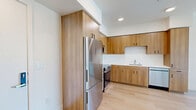 Located on the fifth floor at 900 Chestnut St in Redwood City, CA, this modern one-bedroom, one-bathroom unit offers a well-designed layout with contemporary finishes throughout. Light hardwood flooring flows seamlessly across every room, complementing the clean white walls and creating a bright, cohesive aesthetic.

The open kitchen is a standout feature, outfitted with warm wood cabinetry extending to the ceiling for generous storage, a full suite of stainless steel appliances including a refrigerator, range, microwave, and dishwasher, and a crisp white tile backsplash. The adjacent living area is open and airy, benefiting from recessed lighting and a wall-mounted mini-split system for efficient climate control.

The bedroom is a comfortable retreat, featuring a large sliding-door closet and a wall-mounted mini-split unit. Corner and oversized windows flood the room with natural light and frame pleasant views of the Redwood City skyline and surrounding hills, adding to the elevated feel of the fifth-floor position.

The bathroom is cleanly appointed with warm wood vanity cabinetry, a white countertop, a large mirror, and light wood-style flooring that ties back to the rest of the unit. Overall, the space presents a modern, move-in-ready design ideal for those seeking comfort and style in the heart of Redwood City.