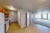 Located at 228 Coffeen St in Watertown, NY, this one-bedroom, one-bathroom unit offers a practical and straightforward single-floor layout. The interior is finished with neutral gray walls throughout, textured ceilings, and a combination of carpet and tile flooring that varies by room.

The living and dining areas flow together in an elongated, open arrangement, carpeted underfoot and illuminated by a window that brings in natural light. Baseboard heating runs along the walls, providing efficient warmth throughout the unit.

The kitchen is positioned adjacent to the main living space and features warm wood-toned cabinetry, white appliances including a range and refrigerator, and light-colored countertops over tile flooring, offering a compact yet complete cooking area.

The bedroom is a well-proportioned carpeted room featuring two windows that allow ample natural light to enter, a baseboard heater, and a built-in closet with bifold doors for convenient storage. Two additional closets are found in the hallway area, providing extra storage capacity.

The bathroom includes a full tub/shower surround, toilet, and vanity, finished with tile flooring and a drop ceiling. The layout is efficient and functional. Overall, the unit presents a clean, no-frills living space well-suited for straightforward everyday living.