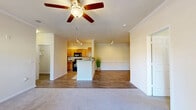 Located at River Falls in Duncan, SC, this well-appointed 3-bedroom, 2-bathroom residence offers a thoughtfully designed single-floor layout with a generous overall footprint. The kitchen is equipped with warm honey-toned cabinetry, dark granite-style countertops, and black appliances including a range, over-the-range microwave, and dishwasher. A pass-through breakfast bar connects the kitchen to the living and dining area, enhancing the open flow of the space. Wood-look flooring runs through the main living areas, while plush carpeting provides comfort in the bedrooms. The living room features crown molding, a ceiling fan with light fixture, and a glass door that opens to an outdoor balcony, filling the space with natural light. The primary bedroom is generously sized and includes a walk-in closet outfitted with multi-tier wire shelving for ample storage. Both bathrooms feature wood-look flooring, warm wood vanities with light countertops, and tub-shower combinations. A dedicated laundry room with wire shelving, wood-look flooring, and washer/dryer hookups adds everyday convenience. Three closets throughout the unit provide additional storage. The overall palette of warm neutrals and clean white trim creates a bright, welcoming ambiance throughout.