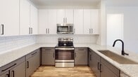 Located at 336 Chestnut Parkway in Indian Trail, NC, this single-floor residence showcases a clean, modern design with thoughtfully selected finishes throughout. The open-concept living and kitchen area features warm wood-look luxury vinyl plank flooring, recessed lighting, and a neutral white palette that creates a bright, welcoming atmosphere. The kitchen is well-appointed with two-tone cabinetry — white upper cabinets paired with gray lower cabinets — complemented by granite countertops, a classic white subway tile backsplash, and a full suite of stainless steel appliances including a French door refrigerator, electric range, and over-the-range microwave. The bedrooms are carpeted for comfort and equipped with ceiling fans and large windows fitted with horizontal blinds, allowing ample natural light. The bathrooms are finished with granite vanity countertops, undermount sinks, black matte fixtures, subway tile tub surrounds, and wood-look flooring. A generously sized walk-in closet with multi-level wire shelving provides substantial storage. Black hardware accents on interior doors and cabinetry add a cohesive, contemporary touch throughout the entire space.