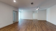 This well-designed single-floor residence offers a clean, contemporary aesthetic throughout its open-concept layout. The expansive living and dining area is finished with rich, warm-toned wood-look flooring, crisp white walls, recessed lighting, and a ceiling fan, creating a bright and inviting atmosphere. A sliding glass door allows natural light to pour in and provides access to the outdoors.

The kitchen is a standout feature, equipped with dark espresso cabinetry, granite countertops, a white subway tile backsplash, and a full suite of stainless steel appliances including a refrigerator, range, microwave, and dishwasher. Pendant lighting over the breakfast bar adds a polished, modern touch.

The bedroom is generously sized, finished with plush carpeting, and includes a walk-in closet with built-in shelving for ample storage. An adjacent en-suite bathroom features a dual-sink vanity with granite countertops, dark cabinetry, framed mirrors, and large-format tile flooring. A second full bathroom offers a tub-shower combination with white subway tile surround, dark cabinetry, and a granite countertop vanity. Together, these spaces reflect a cohesive, modern design with quality finishes throughout.
