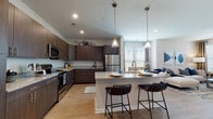 Located at 12525 Oldehurst Place in Charlotte, NC, this well-appointed single-floor residence offers a thoughtfully designed open-concept layout with contemporary finishes throughout. The kitchen serves as a central hub of the home, showcasing rich dark wood cabinetry extending to the ceiling, granite countertops, and a full suite of stainless steel appliances including a refrigerator, electric range, and microwave. A large island with pendant lighting and seating provides an ideal space for casual dining and entertaining, while wood-look flooring ties the kitchen seamlessly into the adjacent living and dining areas. The living room is filled with natural light from multiple windows dressed with blinds and draping curtains, creating a warm and inviting atmosphere. The bedrooms are generously sized, each featuring plush carpeting, ample natural light, and ceiling fans for year-round comfort. The bathroom is cleanly finished with wood-look flooring, a granite-topped vanity with dark wood cabinetry, and a full tub-shower combination with classic white tile surround. Neutral wall tones and consistent modern finishes throughout the space lend a cohesive, polished aesthetic that balances style and functionality.