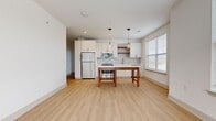 Located at 2100 Marquis Pkwy in Williamsburg, VA, this single-floor, three-bedroom, one-bathroom unit offers a well-designed layout with contemporary finishes throughout. The open-concept kitchen and living area serves as the heart of the home, featuring light wood-style flooring, white shaker cabinetry, a tile backsplash, stainless steel appliances, and stylish pendant lighting. Natural light filters in through multiple windows fitted with blinds, enhancing the clean, modern aesthetic.

The three bedrooms are carpeted for comfort, each equipped with ceiling fans and windows that bring in natural light. The spacious primary bedroom includes a double-door closet with matte black hardware, adding a refined touch. The additional bedrooms offer views of the surrounding neighborhood.

The bathroom is sleekly designed with light wood-style flooring, white cabinetry with black hardware, a white countertop vanity, and a tiled shower-tub combination. Two hallways connect the living spaces efficiently, and a dedicated closet provides additional storage. The living room offers access to an exterior door alongside multiple windows, creating an airy and well-lit atmosphere throughout.