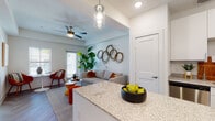 This single-story residence is thoughtfully designed with a open-concept layout that connects the kitchen and living areas into one cohesive, light-filled space. The kitchen is well-appointed with stainless steel appliances, including a range, microwave, dishwasher, and French door refrigerator. White shaker-style cabinetry reaches toward the ceiling, complemented by granite countertops and a central island with dark lower cabinetry, providing additional prep space and storage. Light wood-look flooring runs throughout, adding warmth and continuity.

The living area benefits from natural light through large windows and a sliding glass door that opens to an outdoor area. A ceiling fan overhead and tray ceiling detailing lend architectural character to the space. Two bedrooms offer comfortable retreats, each featuring ceiling fans, tray ceilings, and windows that bring in natural light. The bathroom is finished with subway tile surrounding the tub-shower combo, granite-topped white vanity, and wood-look flooring, maintaining the home's clean, modern aesthetic throughout.