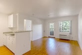 Located in the Willow Glen neighborhood of San Jose, California, this one-bedroom, one-bathroom residence offers a well-organized single-floor layout designed for efficient, comfortable living. The open living area features warm wood-look flooring, neutral white walls, and a wall-unit HVAC system. A glass-paneled door leads to a private balcony, while an adjacent window frames views of surrounding greenery, filling the space with natural light and a connection to the outdoors. The kitchen is efficiently designed with a peninsula countertop finished in light granite, white cabinetry, and matching white appliances including a refrigerator and range. A dedicated built-in cabinet nook near the entry provides additional storage and workspace. The bedroom is carpeted for warmth and comfort, featuring a corner window configuration that brings in ample daylight and pleasant outdoor views, along with a closet for organized storage. A second closet elsewhere in the unit adds further convenience. The bathroom is clean and functional, appointed with wood-look flooring, a full tub-shower combination with accessibility grab bars, and a vanity. Throughout the residence, the bright white palette and consistent finishes create a cohesive, well-maintained ambiance suited for everyday living.