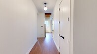 This 530 square foot apartment offers a thoughtful blend of compact living and modern design. The space features two bedrooms, one bathroom, and an open-concept layout that maximizes every inch of its single-floor plan. Rich wood flooring runs throughout, creating a warm and inviting atmosphere. The living areas are adorned with a striking wooden ceiling, adding character and height to the rooms.

Large windows in the bedrooms and living spaces flood the apartment with natural light, offering views of the surrounding urban landscape. The primary bedroom, measuring 110 square feet, provides a cozy retreat. The modern kitchen is a standout feature, boasting sleek white cabinetry, stainless steel appliances, and a stylish marble-look backsplash. Recessed lighting and under-cabinet illumination enhance the kitchen's functionality and aesthetic appeal.

The bathroom, while compact, is designed with a clean, minimalist approach, featuring a white palette and modern fixtures. Two hallways contribute to the efficient flow of the space, connecting the various rooms seamlessly. Despite its modest size, this apartment demonstrates how thoughtful design can create a comfortable and stylish living environment in an urban setting.