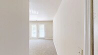 Located at 126 Candlewood Way in Newport News, Virginia, this single-floor, 2-bedroom, 2-bathroom home offers a practical and comfortable layout. The living area is bright and open, featuring soft neutral-toned carpet underfoot and a sliding glass door that provides access to an outdoor balcony, allowing natural light to flow through the space. A textured ceiling detail adds visual interest overhead.

The kitchen is positioned adjacent to the living area and features warm medium-toned wood cabinetry, a countertop with an integrated sink, and tile flooring that contrasts neatly with the carpeted living spaces. The open sightlines between the kitchen and main living area create a cohesive, connected feel.

Both bedrooms are carpeted and finished in soft neutral tones, each with windows that bring in natural light and views of surrounding greenery. Each bedroom includes access to a walk-in closet, providing practical storage solutions.

The two bathrooms are finished with tile flooring and warm wood vanity cabinetry with light countertops. One bathroom features a full tub-shower combination with brushed nickel fixtures, while the other conveniently houses a stacked in-unit washer and dryer, adding everyday practicality. A hallway connects the rooms, completing this well-organized and efficiently designed home.