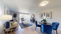 This single-floor residence offers a thoughtfully designed layout that maximizes both comfort and functionality. The open-concept living and dining area is anchored by light wood-style flooring, neutral walls, and a sliding glass door that floods the space with natural light while providing access to an outdoor balcony. The living area is generously proportioned, offering ample room for seating and relaxation, while the adjacent dining space features built-in display shelving that adds architectural character and practical storage.

The galley-style kitchen is efficiently arranged, featuring white cabinetry, a gas range with a sleek overhead hood vent, a stainless steel refrigerator, and a double sink — all set against light countertops. A pass-through opening connects the kitchen to the dining area, enhancing the sense of openness.

The bedroom is a serene retreat with plush carpeting, a large window fitted with slatted blinds that allow for natural light and outdoor views, and ample closet space. The full bathroom is finished with large-format tile in the tub/shower surround, light wood-style flooring, a vanity with a granite-style countertop, and a framed mirror, creating a clean and contemporary feel throughout.