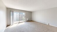 Located at 1930 E 86th St in Bloomington, MN, this two-bedroom, one-bathroom apartment offers a functional and comfortable single-floor layout. The galley-style kitchen features wood-look flooring, white cabinetry with ample upper and lower storage, a full suite of white appliances including a range, built-in microwave, and refrigerator, along with a sink positioned beneath overhead cabinets for efficient use of space.

The spacious living room is carpeted and filled with natural light, courtesy of a large sliding glass door that opens to a private balcony with views of the surrounding neighborhood. Baseboard heating runs along the perimeter walls, and a wall-mounted AC unit ensures year-round comfort.

Both bedrooms are carpeted and well-lit, each featuring windows that bring in natural light. The primary bedroom is generously sized and includes a walk-in closet outfitted with wire shelving on multiple walls, offering excellent organization capacity. A second closet with bifold doors provides additional storage nearby.

The full bathroom includes a tiled tub and shower surround, a toilet, and wood-look flooring, maintaining a clean and practical aesthetic throughout. Neutral gray walls and textured ceilings are consistent across the unit, creating a cohesive and understated interior style.